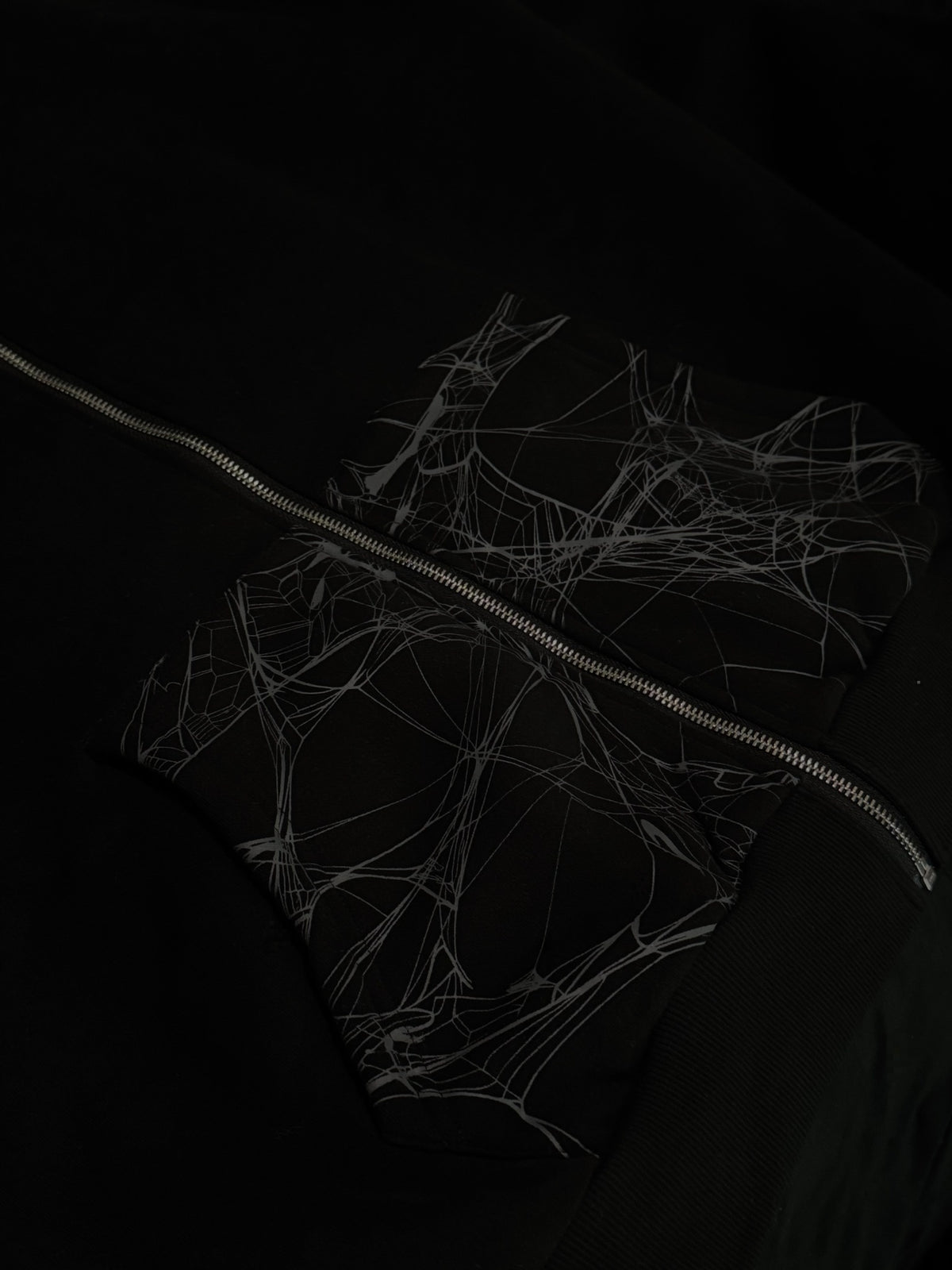 Close-up of Webster hoodie spiderweb pockets and silver-tone zipper